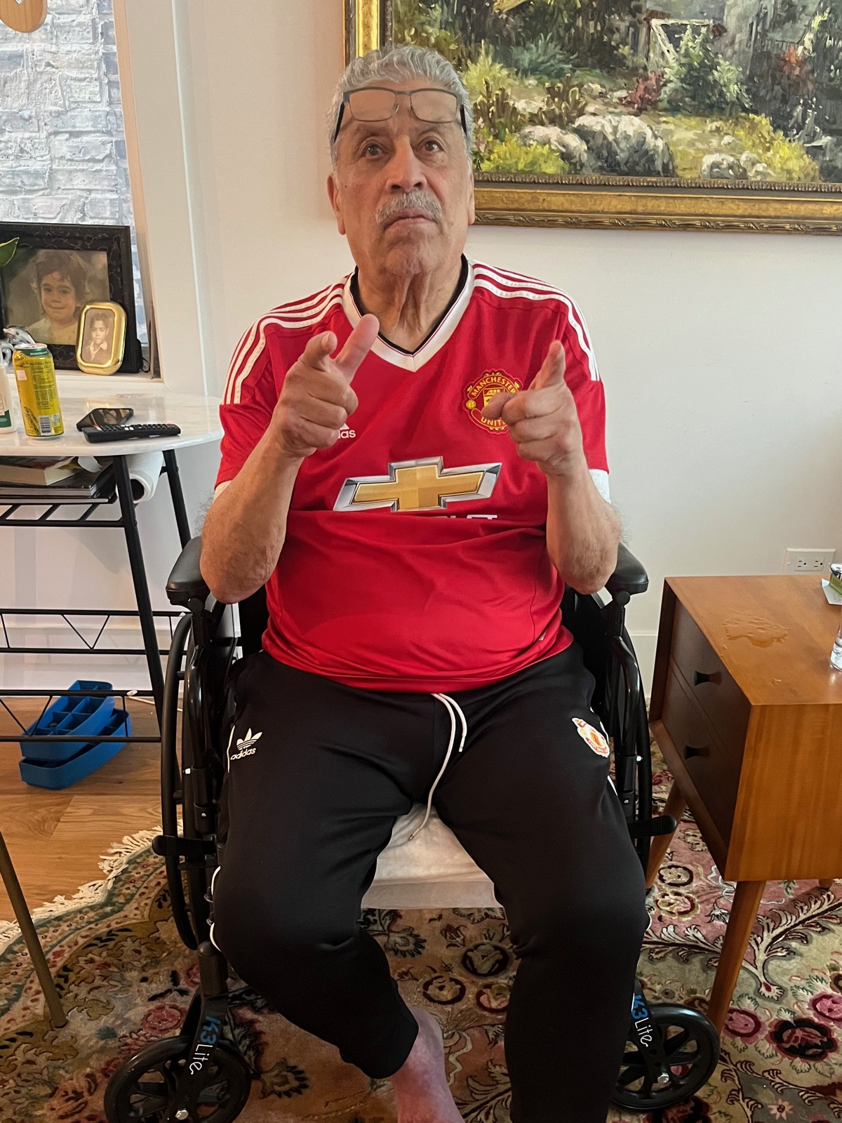 Jamal back at home in his wheelchair, pointing at the camera.